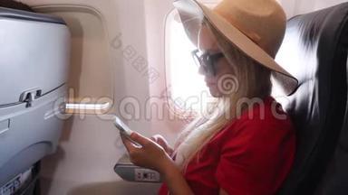 日落时分，戴着帽子的游客坐在飞机窗户附近，飞行时使用手机